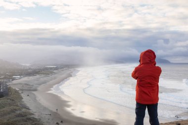 Maceracı bir kamera ile fotoğraf ayakta çekimi güzel Beach canlı kış gün doğumu sırasında adamdır. Cape Kiwanda, Pacific City, Oregon kıyılarında, Amerika'da alınan.
