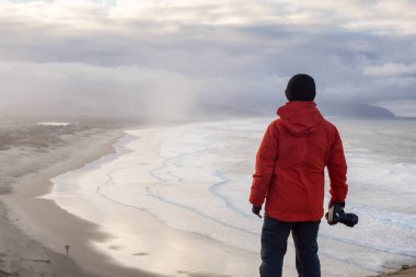 Maceracı bir kamera ile fotoğraf ayakta çekimi güzel Beach canlı kış gün doğumu sırasında adamdır. Cape Kiwanda, Pacific City, Oregon kıyılarında, Amerika'da alınan.