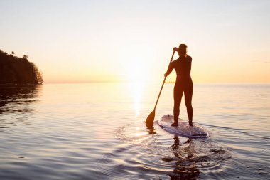Maceracı bir kürek gemide paddeling bir parlak ve canlı gün batımı sırasında kızdır. Alınan İspanyolca bankalar, Vancouver, British Columbia, Kanada.