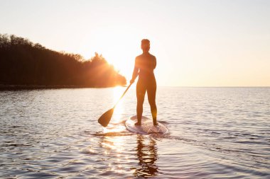 Maceracı bir kürek gemide paddeling bir parlak ve canlı gün batımı sırasında kızdır. Alınan İspanyolca bankalar, Vancouver, British Columbia, Kanada.