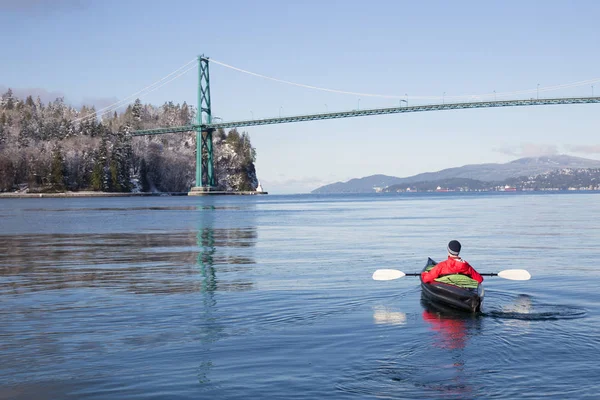 Adventurous man kayaking on an inflatable kayak near Lions Gate Bridge. Taken in North Vancouver, British Columbia, Canada.