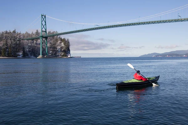 Adventurous man kayaking on an inflatable kayak near Lions Gate Bridge. Taken in North Vancouver, British Columbia, Canada.