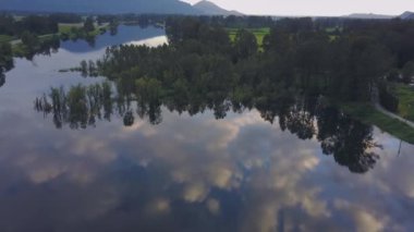 Ağaçlar ve bulutların gökyüzünde renkli bir yansıması bir bahar gün batımı sırasında bataklık gölün güzel hava doğa görünümü. Alınan görev, East of Vancouver, British Columbia, Kanada.