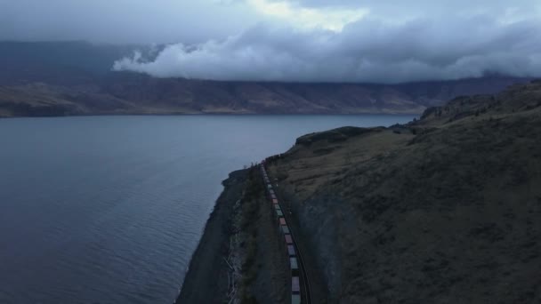 空中ドローン曲線鉄道 曇り秋の日の出の間に湖近くの列車のパノラマの景観 ブリティッシュ コロンビア州 カナダのインテリアは — ストック動画