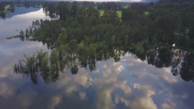 Ağaçlar ve bulutların gökyüzünde renkli bir yansıması bir bahar gün batımı sırasında bataklık gölün güzel hava doğa görünümü. Alınan görev, East of Vancouver, British Columbia, Kanada.