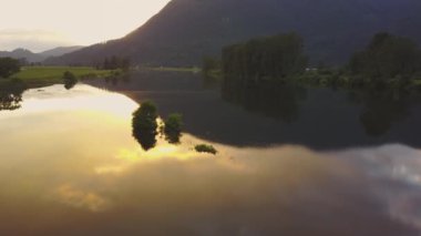 Ağaçlar ve bulutların gökyüzünde renkli bir yansıması bir bahar gün batımı sırasında bataklık gölün güzel hava doğa görünümü. Alınan görev, East of Vancouver, British Columbia, Kanada.