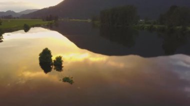 Ağaçlar ve bulutların gökyüzünde renkli bir yansıması bir bahar gün batımı sırasında bataklık gölün güzel hava doğa görünümü. Alınan görev, East of Vancouver, British Columbia, Kanada.