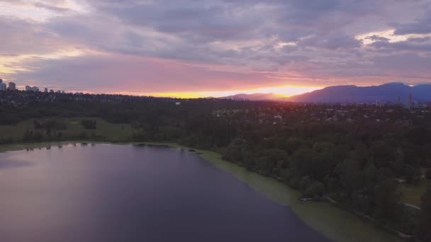 赤い色の空とカラフルで活気のある日没時に都市公園の湖の美しい空中映像 ディア レイク バーナビーより大きいバンクーバー カナダでの撮影 — ストック動画