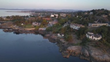Havadan görünümü güzel bir Pasifik Okyanusu sahne ile kayalık sahil üstünde lüks evler. Sermaye Şehir Victoria içinde Vancouver Adası, British Columbia, Kanada, gündoğumu sırasında alınan.