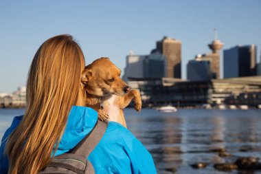 Kız küçük köpeğini, Chihuahua, holding ve şehir merkezinde şehrin güzel manzarayı. Stanley Park, Vancouver, British Columbia, Kanada alınan.