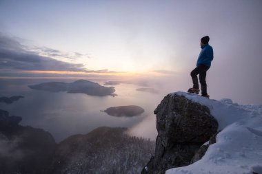 Sarp bir uçurum kenarında güzel bir canlı gün batımı sırasında ayakta maceracı adam. Üstünde tepe-in St Mark's Peak, Kuzey Vancouver, Bc, Kanada alınan.