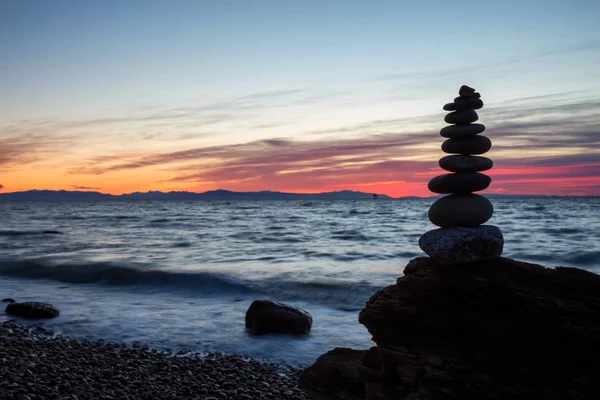 Stack of Rocks piled up by the ocean during a colorful sunset. Taken in Wreck Beach, Vancouver, British Columbia, Canada.