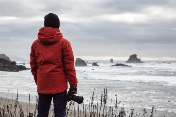 有摄像头的人正在看着一个美丽的太平洋海岸 背景上有崎岖的岩石形成 拍摄于 Ecola 州立公园 大炮海滩 俄勒冈州 — 图库照片