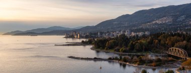West Vancouver, British Columbia, Kanada. Pasifik Okyanusu kıyısındaki günbatımının güneşli ve bulutlu sonbahar günbatımında modern şehir manzarası.
