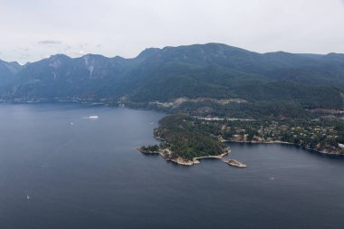 Horseshoe Bay, West Vancouver, British Columbia, Kanada. Yaz günü Kanada Dağ Manzarası ile çevrili kentteki evler, marina ve feribot terminali havadan izleniyor..