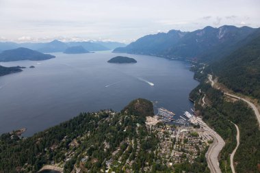 Horseshoe Bay, West Vancouver, British Columbia, Kanada. Yaz günü Kanada Dağ Manzarası ile çevrili kentteki evler, marina ve feribot terminali havadan izleniyor..