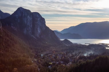 Squamish, North of Vancouver, British Columbia, Canada. Beautiful View from the top of the Mountain of a small town surrounded by Canadian Nature during Autumn Sunset. clipart