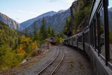 Skagway, Alaska, ABD - 24 Eylül 2019: Eski Tarihi Demiryolu Treni bulutlu bir yaz sabahı turistlerle birlikte Beyaz Geçit 'e çıkıyor.