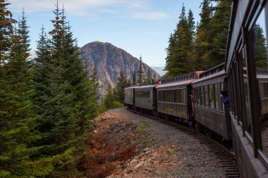 Skagway, Alaska, ABD - 24 Eylül 2019: Eski Tarihi Demiryolu Treni bulutlu bir yaz sabahı turistlerle birlikte Beyaz Geçit 'e çıkıyor.
