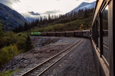 Skagway, Alaska, ABD - 24 Eylül 2019: Eski Tarihi Demiryolu Treni bulutlu bir yaz sabahı turistlerle birlikte Beyaz Geçit 'e çıkıyor.