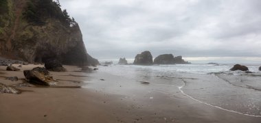 Ecola State Park, Cannon Beach, Oregon, ABD. Pasifik Okyanusu kıyısındaki Sandy ve Rocky Sahili 'nin güzel Panoramik Manzarası bulutlu bir yaz gündoğumu sırasında.