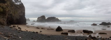 Ecola State Park, Cannon Beach, Oregon, ABD. Pasifik Okyanusu kıyısındaki Sandy ve Rocky Sahili 'nin güzel Panoramik Manzarası bulutlu bir yaz gündoğumu sırasında.