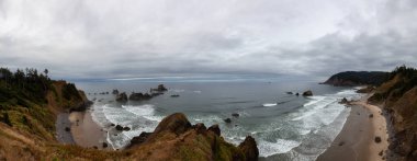 Ecola State Park, Cannon Beach, Oregon, ABD. Pasifik Okyanusu kıyısındaki Sandy ve Rocky Sahili 'nin güzel Panoramik Manzarası bulutlu bir yaz gündoğumu sırasında.