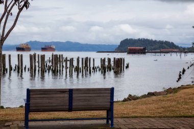 Astoria, Oregon, Birleşik Devletler. Bulutlu bir yaz sabahı, Columbia Nehri manzaralı ahşap bir bankın güzel manzarası..