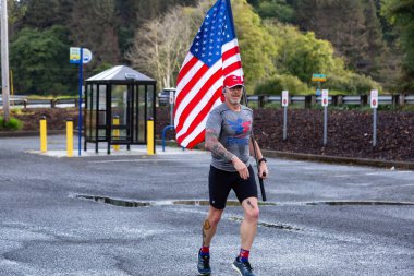Neskowin, Oregon, ABD - 8 Eylül 2019: Rwb Takımı 'nın gururlu üyesi bir yaz sabahı bir Amerikan Bayrağı ile dışarıda koşuyor.