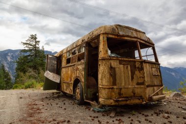 Eski, Paslı, Kırık ve Terk Edilmiş Otobüs Dağ Vadisi 'nde bir göl kenarında bulutlu bir yaz akşamı. Anderson Lake Rd 'de çekildi, Lillooet, Bc, Kanada yakınlarında..