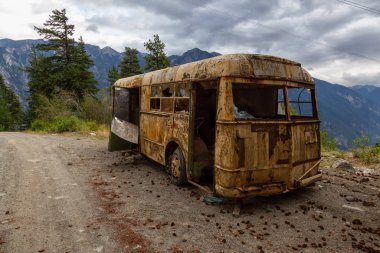 Eski, Paslı, Kırık ve Terk Edilmiş Otobüs Dağ Vadisi 'nde bir göl kenarında bulutlu bir yaz akşamı. Anderson Lake Rd 'de çekildi, Lillooet, Bc, Kanada yakınlarında..