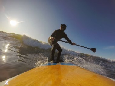 Maceraperest sörfçü adam sonbahar sezonunda güneşli bir sabahta okyanusta sörf yapıyor. Long Beach, Tofino, Vancouver Adası, Bc, Kanada.