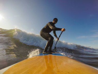 Maceraperest sörfçü adam sonbahar sezonunda güneşli bir sabahta okyanusta sörf yapıyor. Long Beach, Tofino, Vancouver Adası, Bc, Kanada.