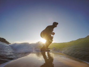 Maceraperest sörfçü adam sonbahar sezonunda güneşli bir sabahta okyanusta sörf yapıyor. Long Beach, Tofino, Vancouver Adası, Bc, Kanada.