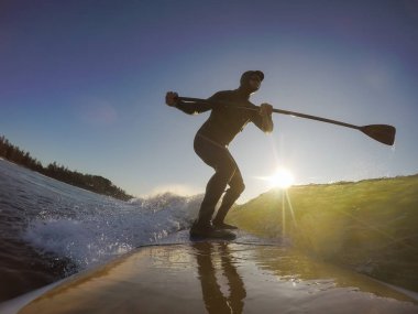 Maceraperest sörfçü adam sonbahar sezonunda güneşli bir sabahta okyanusta sörf yapıyor. Long Beach, Tofino, Vancouver Adası, Bc, Kanada.