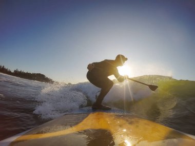 Maceraperest sörfçü adam sonbahar sezonunda güneşli bir sabahta okyanusta sörf yapıyor. Long Beach, Tofino, Vancouver Adası, Bc, Kanada.
