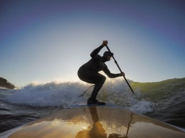 Maceraperest sörfçü adam sonbahar sezonunda güneşli bir sabahta okyanusta sörf yapıyor. Long Beach, Tofino, Vancouver Adası, Bc, Kanada.
