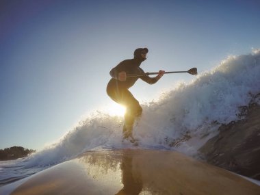 Maceraperest sörfçü adam sonbahar sezonunda güneşli bir sabahta okyanusta sörf yapıyor. Long Beach, Tofino, Vancouver Adası, Bc, Kanada.
