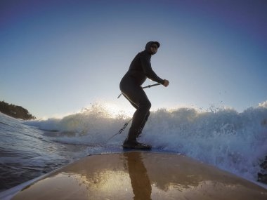 Maceraperest sörfçü adam sonbahar sezonunda güneşli bir sabahta okyanusta sörf yapıyor. Long Beach, Tofino, Vancouver Adası, Bc, Kanada.