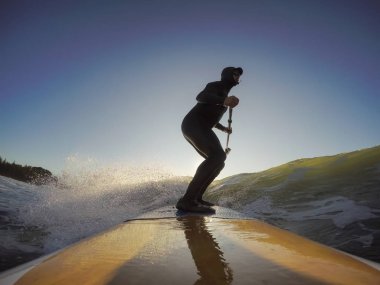 Maceraperest sörfçü adam sonbahar sezonunda güneşli bir sabahta okyanusta sörf yapıyor. Long Beach, Tofino, Vancouver Adası, Bc, Kanada.
