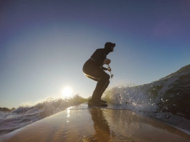 Maceraperest sörfçü adam sonbahar sezonunda güneşli bir sabahta okyanusta sörf yapıyor. Long Beach, Tofino, Vancouver Adası, Bc, Kanada.