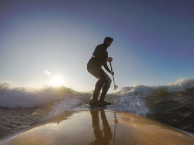 Maceraperest sörfçü adam sonbahar sezonunda güneşli bir sabahta okyanusta sörf yapıyor. Long Beach, Tofino, Vancouver Adası, Bc, Kanada.