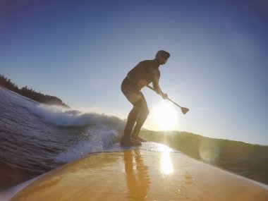 Maceraperest sörfçü adam sonbahar sezonunda güneşli bir sabahta okyanusta sörf yapıyor. Long Beach, Tofino, Vancouver Adası, Bc, Kanada.