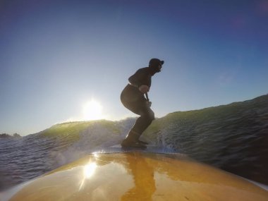 Maceraperest sörfçü adam sonbahar sezonunda güneşli bir sabahta okyanusta sörf yapıyor. Long Beach, Tofino, Vancouver Adası, Bc, Kanada.