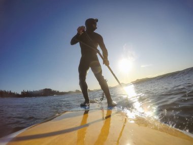 Maceraperest sörfçü adam sonbahar sezonunda güneşli bir sabahta okyanusta sörf yapıyor. Long Beach, Tofino, Vancouver Adası, Bc, Kanada.