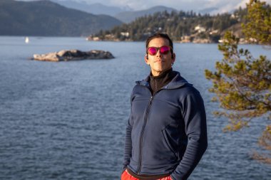 Bulutlu ve güneşli bir günbatımında, doğada, Maceracı bir Latin adamın portresi. Deniz Feneri Parkı, At Nalı Koyu, Batı Vancouver, Bc, Kanada.