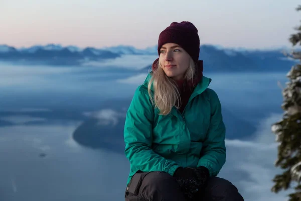 Renkli Kış Günbatımında Kar Kaplı Bir Dağın Tepesinde Oturan Maceraperest — Stok fotoğraf