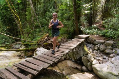 Hayat dolu bir yaz gününde Ormanda Koşan Maceracı Kız Patikası. Deep Cove, North Vancouver, British Columbia, Kanada 'da çekildi..