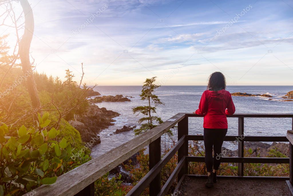 Wild Pacifc Trail, Ucluelet, Vancouver Island, BC, Canada. Girl Enjoyin the Beautiful View of the Rocky Ocean Coast during a colorful and vibrant morning sunrise.
