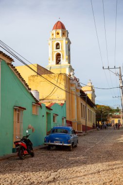 Trinidad, Küba - 12 Haziran 2019: Canlı güneşli gün batımında küçük bir Küba Kasabasının sokaklarında eski bir Klasik Amerikan Arabasının manzarası.
